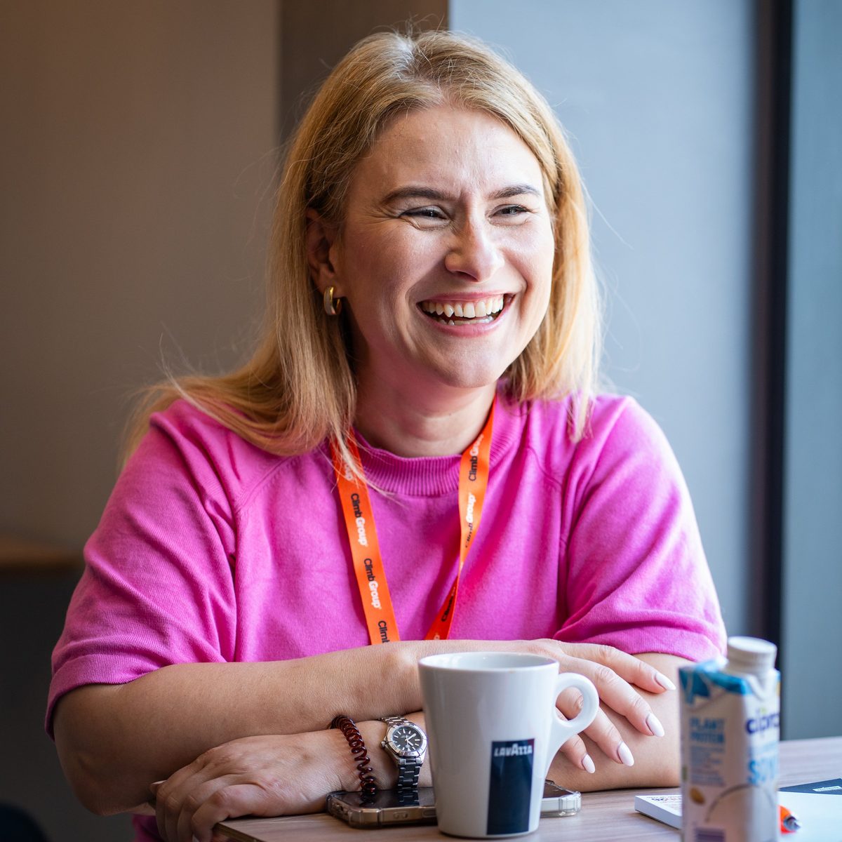 A delegate in an orange lanyard laughing during a table conversation